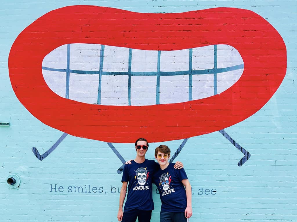 father and son posing in front of austin texas murals