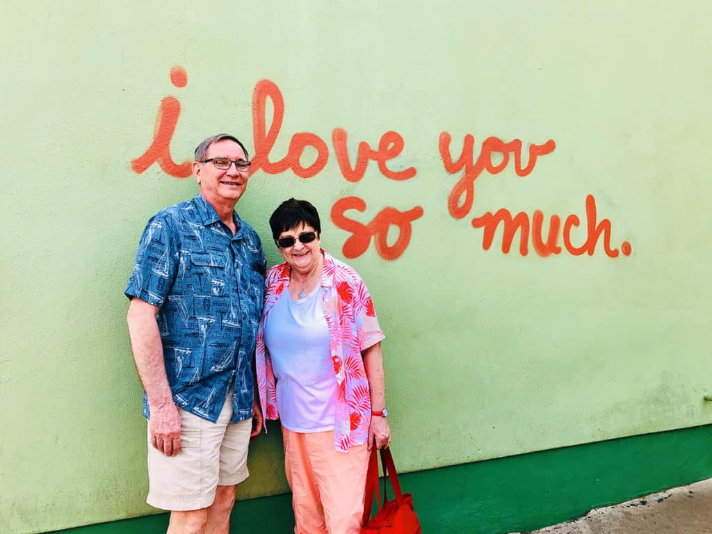 father day photoshoot ideas older couple standing in front of the i love you so much red graffiti wall
