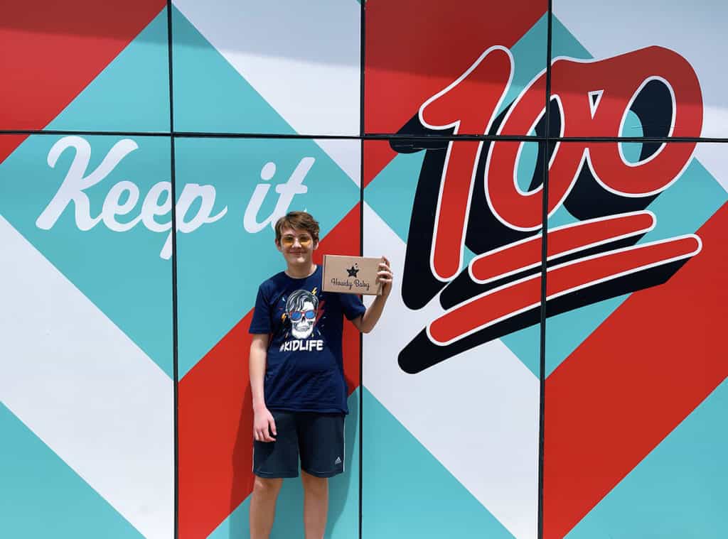 Teen boy posing in front of keeping it 100 wall at P. Terry's Burger Stand